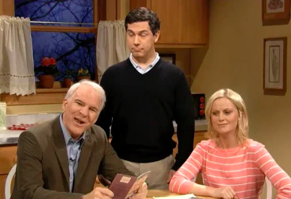 Screenshot of above video showing Steve Martin, Amy Poehler, and another Saturday Night Live cast member talking at a kitchen table.